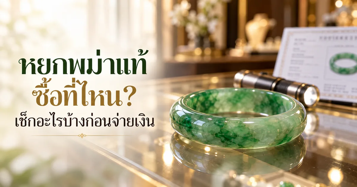 กำไลหยกพม่าสีเขียวบนเคาน์เตอร์ร้านเครื่องประดับในแสงธรรมชาติ ด้านหลังมีไฟฉายเล็กและการ์ดใบรับรองที่เบลอ พร้อมหัวข้อ หยกพม่าแท้ ซื้อที่ไหน?