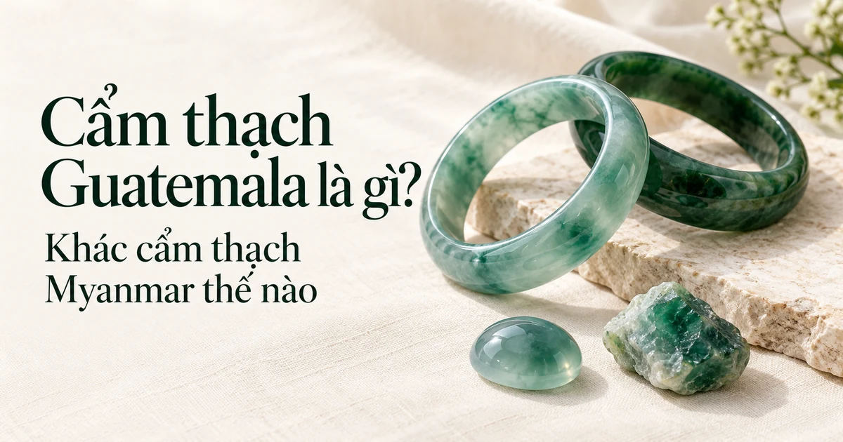 Những chiếc vòng cẩm thạch xanh ngả lam và xanh đậm bên một mặt cabochon lam thủy trong và một viên phỉ thúy thô trên vải lanh màu ngà