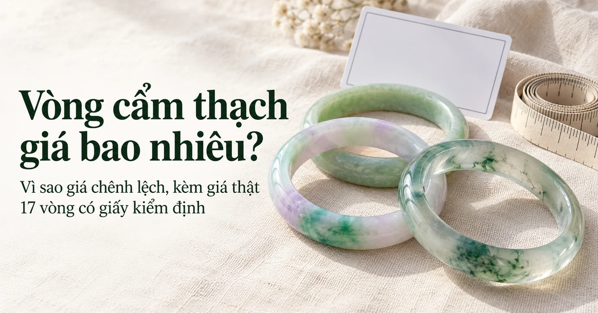 Ba chiếc vòng phỉ thúy khác chủng và màu bên cạnh tấm thẻ giấy kiểm định nhỏ và cuộn thước dây trên vải lanh màu ngà, ánh sáng ban ngày dịu