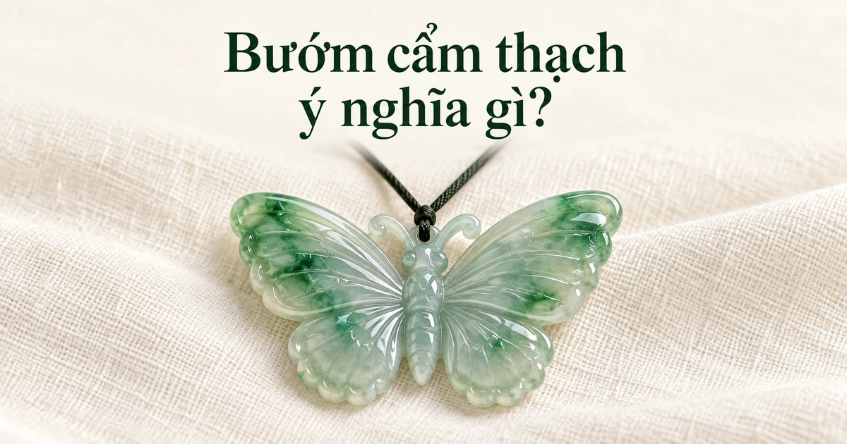 Một mặt dây phỉ thúy chất băng chạm hình con bướm, cánh ánh xanh lục nhẹ, xỏ dây mảnh màu tối, đặt trên vải lanh màu ngà dưới ánh sáng ban ngày dịu