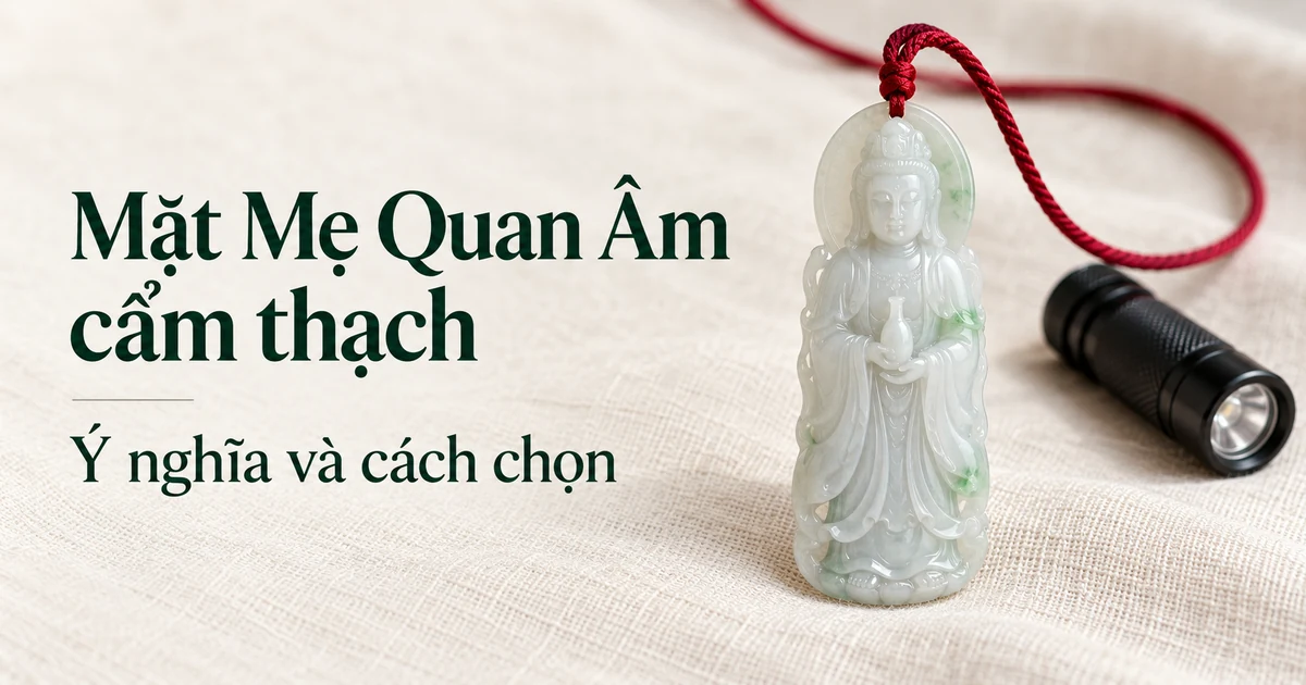 Mặt Quan Âm đứng bằng cẩm thạch loại băng ánh xanh nhạt đeo dây dù đỏ, đặt trên vải lanh màu ngà cạnh một đèn pin nhỏ trong ánh sáng ban ngày dịu, kèm tiêu đề Mặt Mẹ Quan Âm cẩm thạch: ý nghĩa và cách chọn