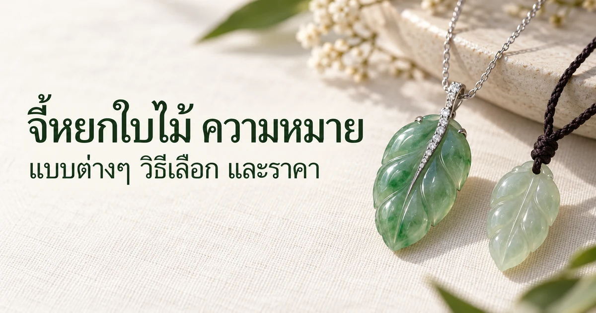จี้หยกพม่ารูปใบไม้สีเขียวตัวเรือนทองขาวบนสร้อยทองขาวเส้นเล็ก วางบนผ้าลินินสีงาช้างข้างใบไม้หยกผิวเรียบใบเล็กกว่าที่ห้อยเชือกถักสีเข้ม ในแสงธรรมชาติอ่อนๆ