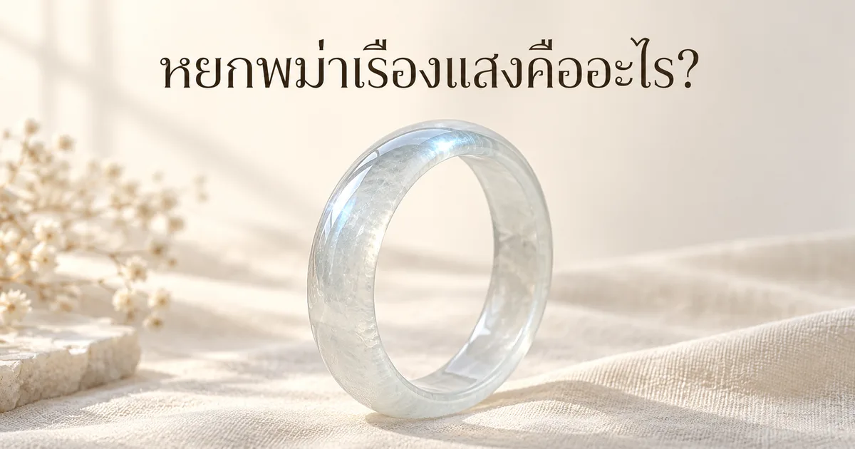 กำไลหยกพม่าเนื้อน้ำแข็งไร้สีบนผ้าลินินสีงาช้างในแสงหน้าต่างนุ่ม ๆ มีแสงขาวอมฟ้าจาง ๆ ลอยตามขอบโค้ง พร้อมหัวข้อ หยกพม่าเรืองแสงคืออะไร?