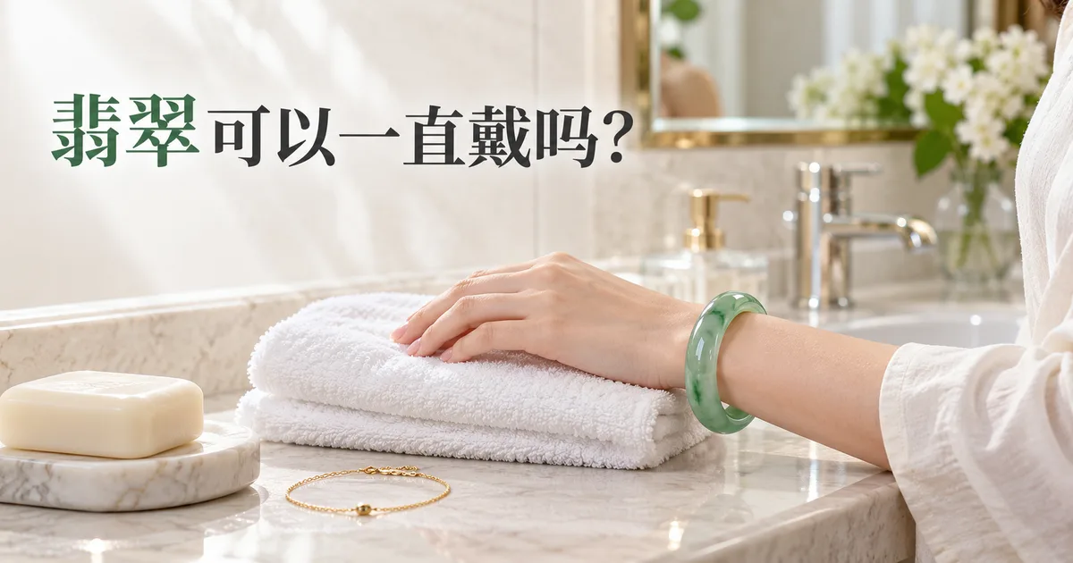 浴室台盆边叠好的白毛巾上,一只戴着绿色翡翠手镯的手,旁边放着香皂和金手链,配标题「翡翠可以一直戴吗?」