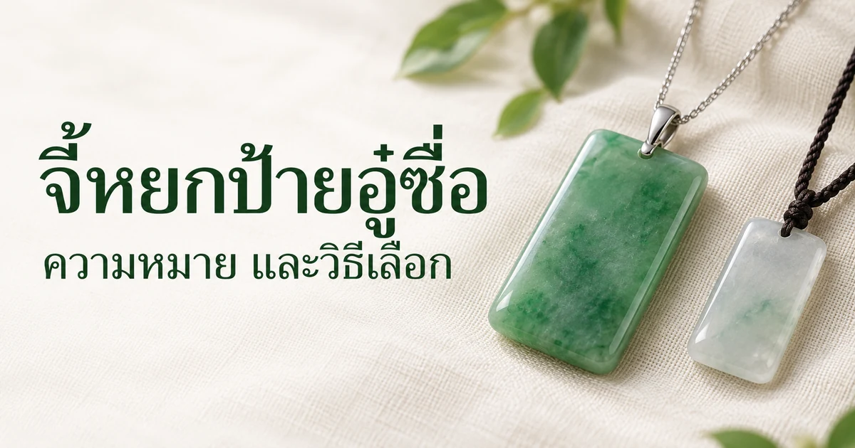 จี้ป้ายอู๋ซื่อหยกพม่าสีเขียวหน้าเรียบ มุมมน ห้อยหูทองขาว 18K เล็กๆ บนสร้อยเส้นเล็ก วางบนผ้าลินินสีงาช้างข้างป้ายสีอ่อนชิ้นเล็กกว่าที่ห้อยเชือกถักสีเข้ม ในแสงธรรมชาติอ่อนๆ